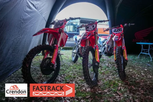 Three red motocross bikes in a tent