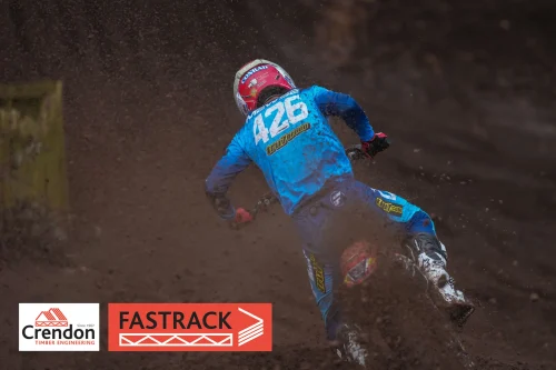 View of the back of a biker in blue on a dirt track.