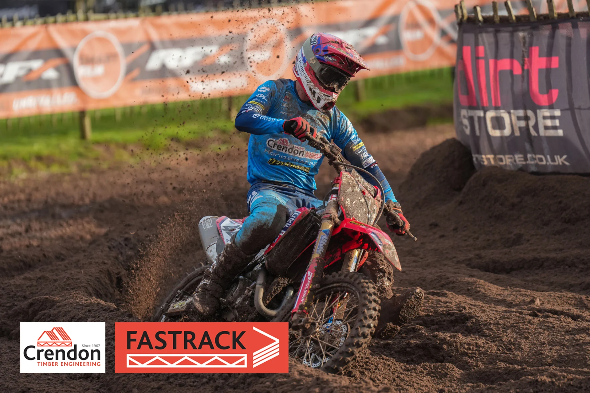 biker in blue on a red bike on a dirt track