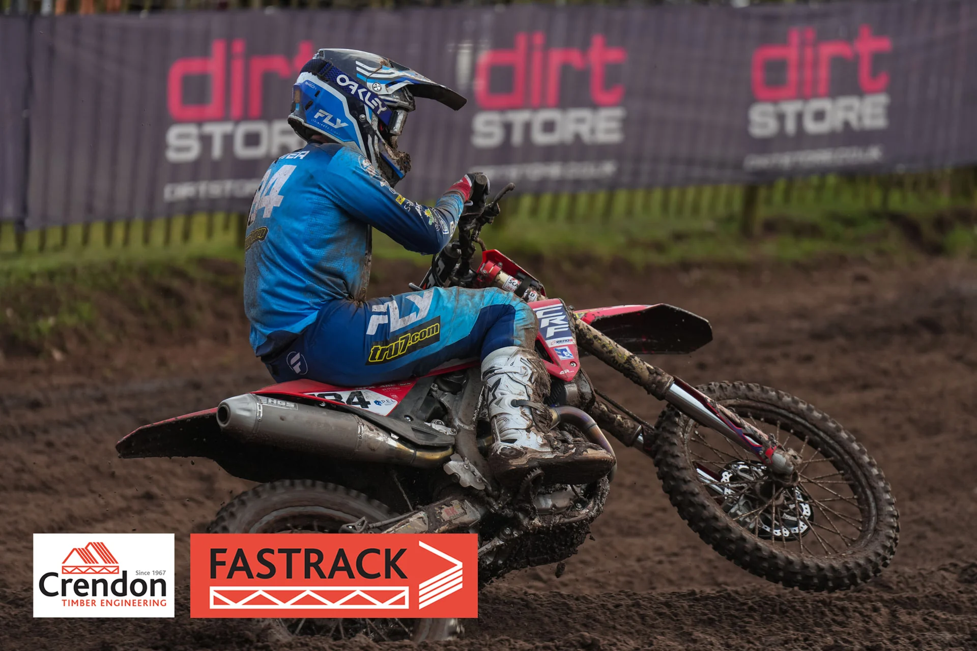 Biker wearing blue on a red bike on a dirt track. 