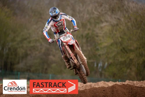 A motocross rider jumping off the dirt track.