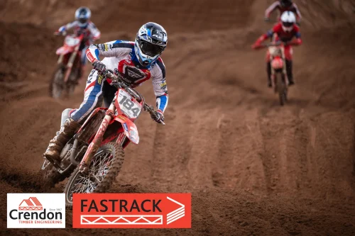 A motocross rider in focus at the front of the picture with two riders in the back. 