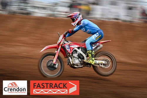 A motocross rider on a dirt track from a side angle. 