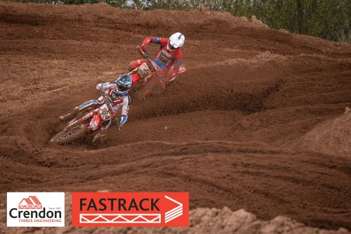 Two motocross riders on a dirt track going round a bend.