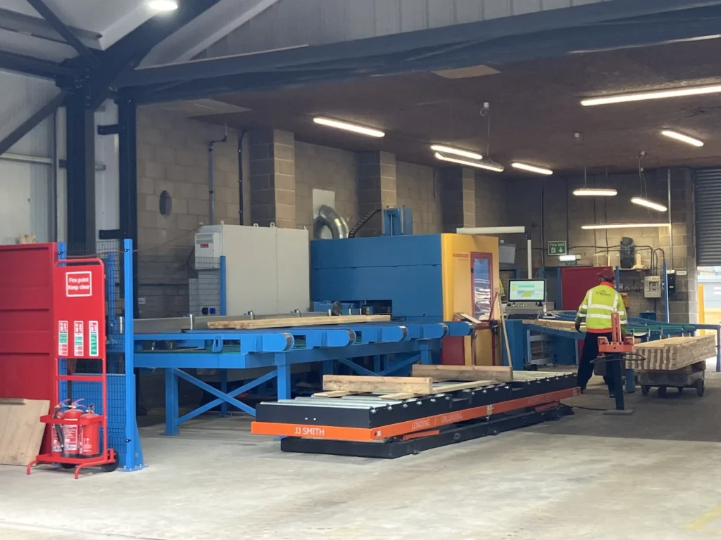 Large machinery being operated by a worker with stacks of materials nearby