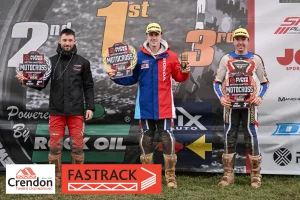 Three motorcross bikers holding trophies on a podium