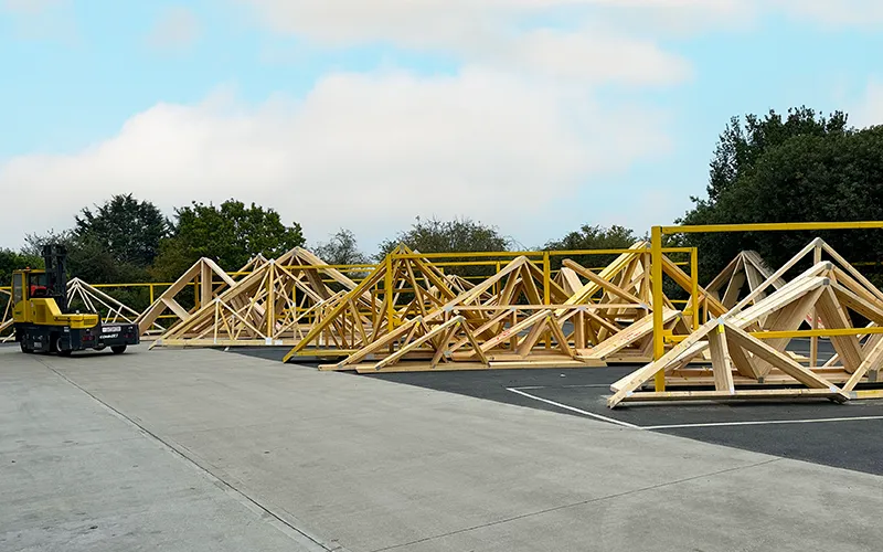 Racks of roof trusses leaning on metal frames in a yard