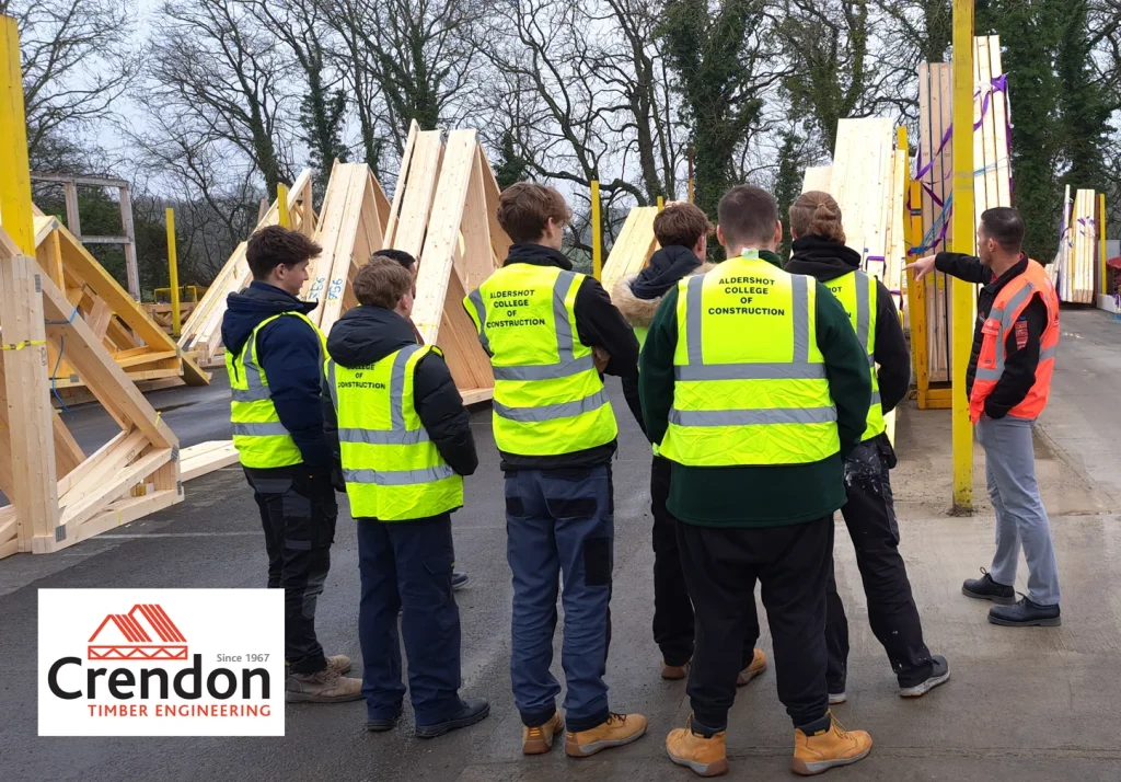 Construction students in High vis being shown the outdoor storage area by a Crendon worker