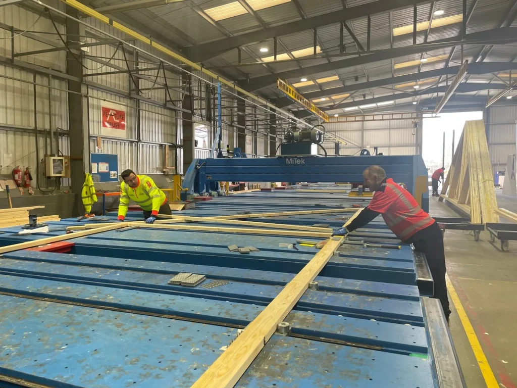 Two workers working with materials on a work bench/machinery