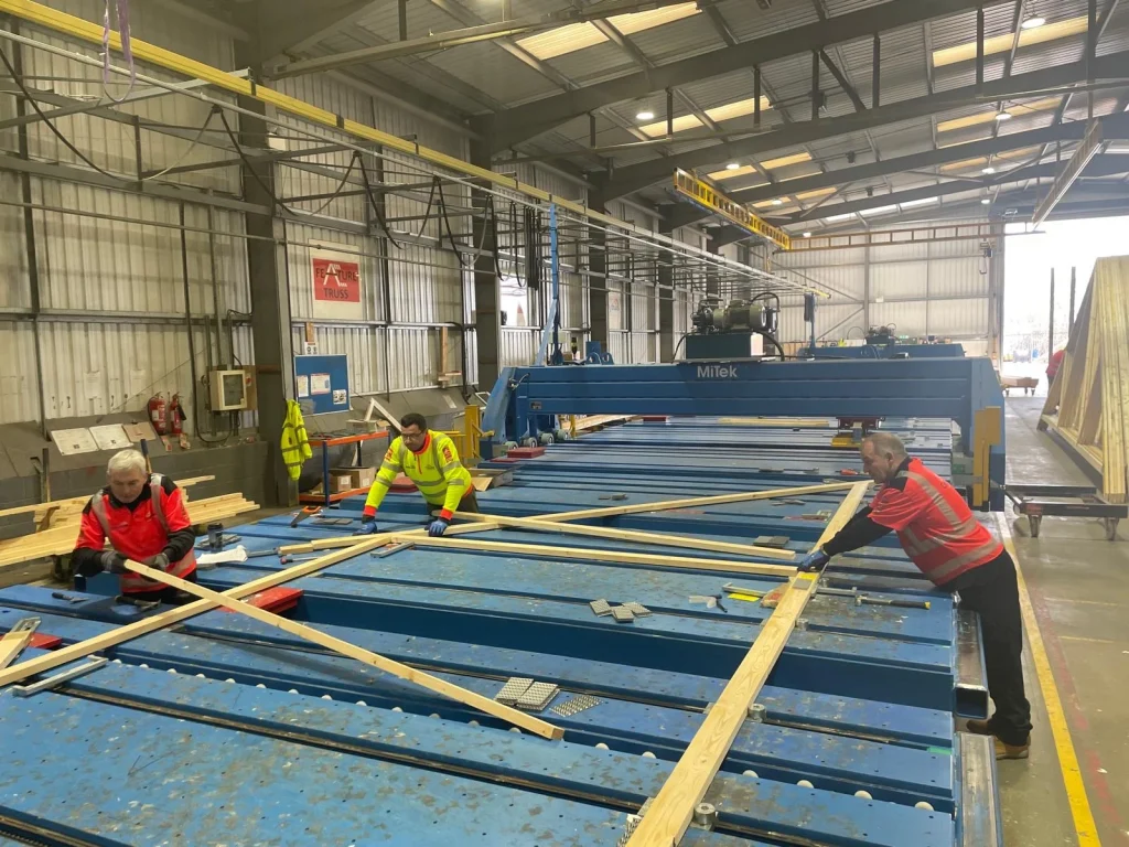Three workers in High-vis working on products on a work bench