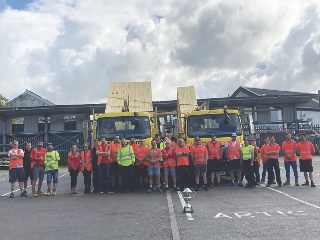 Crendon team posing in front of two lorries and behind a silver cup