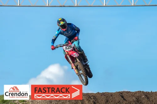 A motocross rider doing a jump off the dirt track.