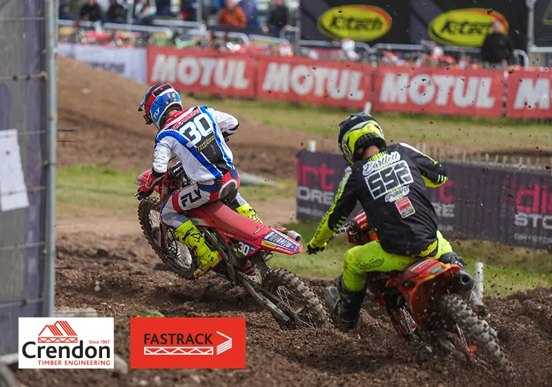 Backs of 2 men on bikes going round a corner on dirt track