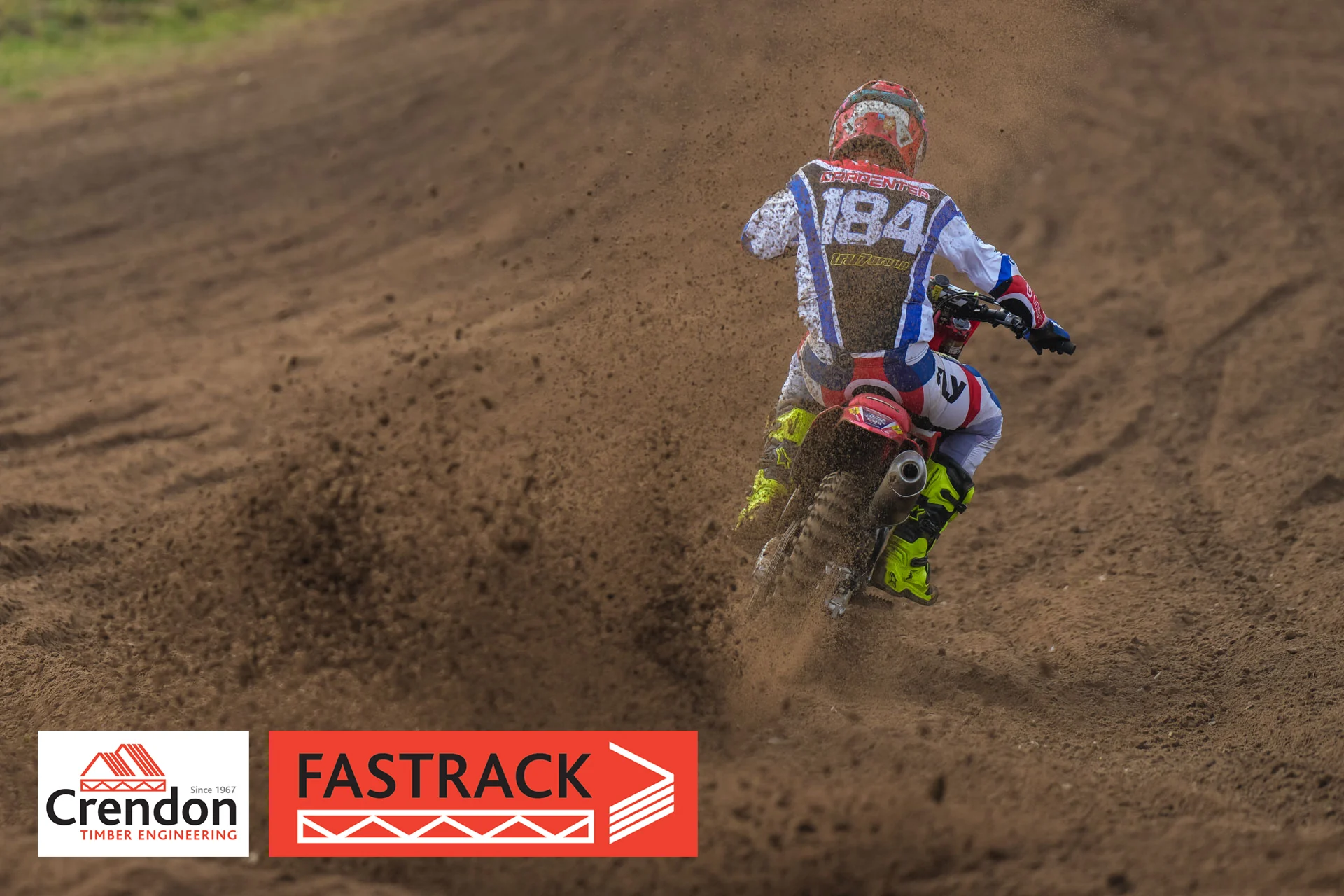 A behind shot of a biker on the dirt track.