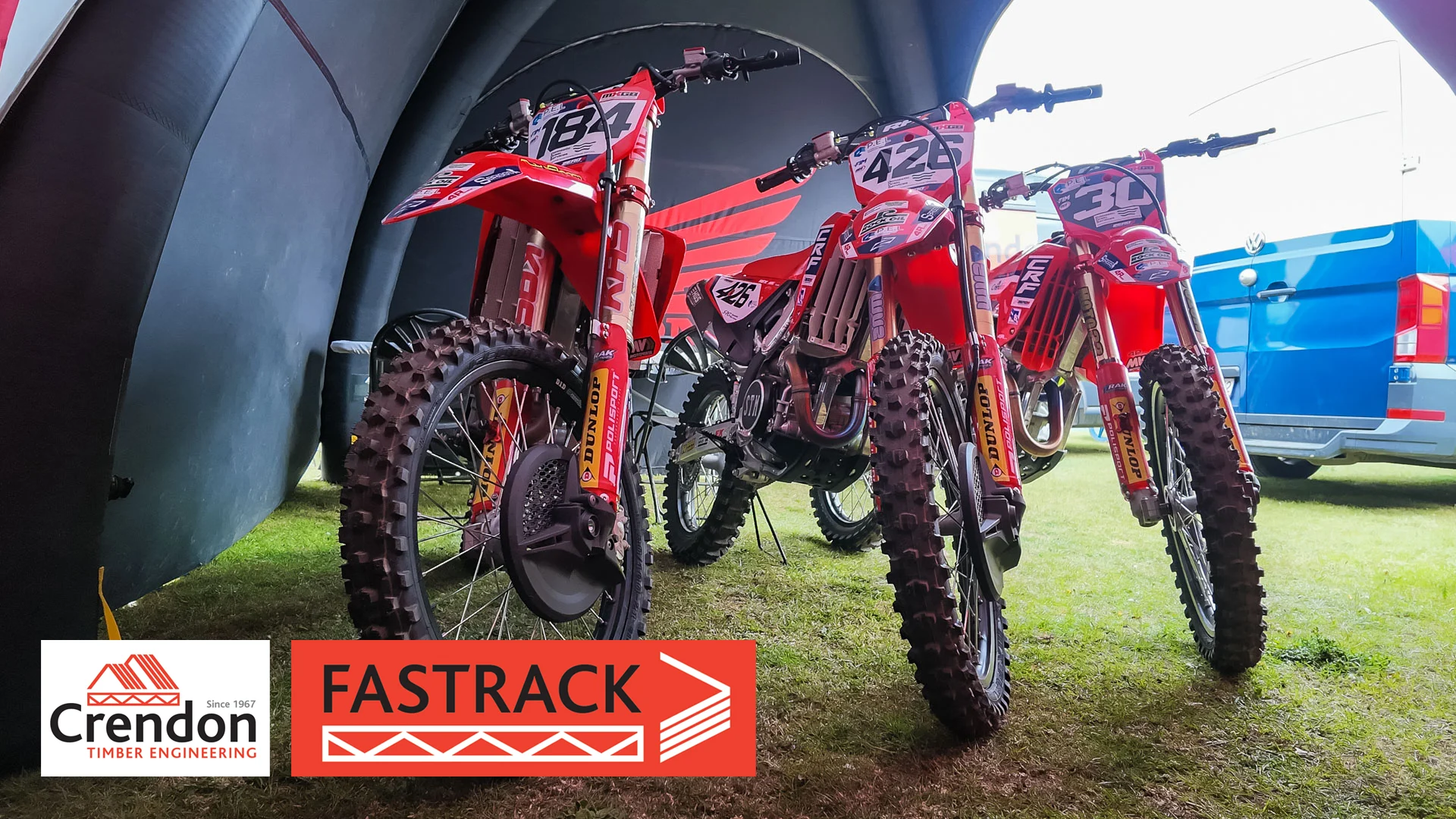 3 motocross bikes lined up in a tent.