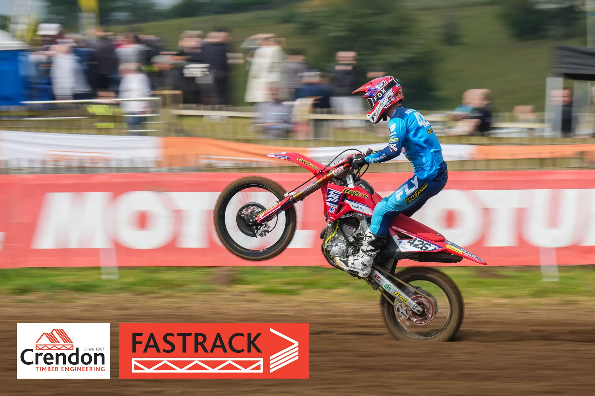 A motocross rider doing a wheelie on the track.