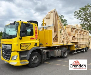 Yellow Crendon Timber Engineering flatbed truck carrying stacked prefabricated timber roof trusses.