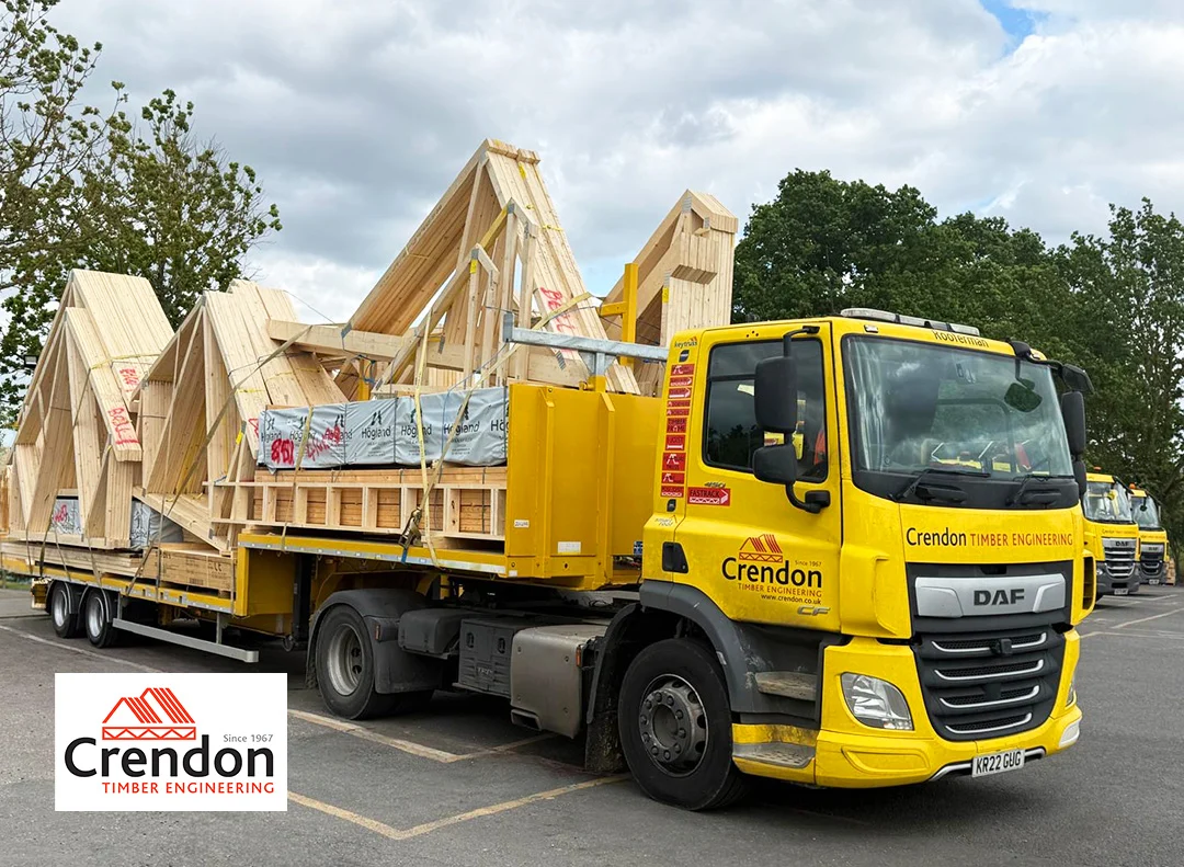 Yellow Crendon Timber Engineering flatbed truck carrying stacked prefabricated timber roof trusses.
